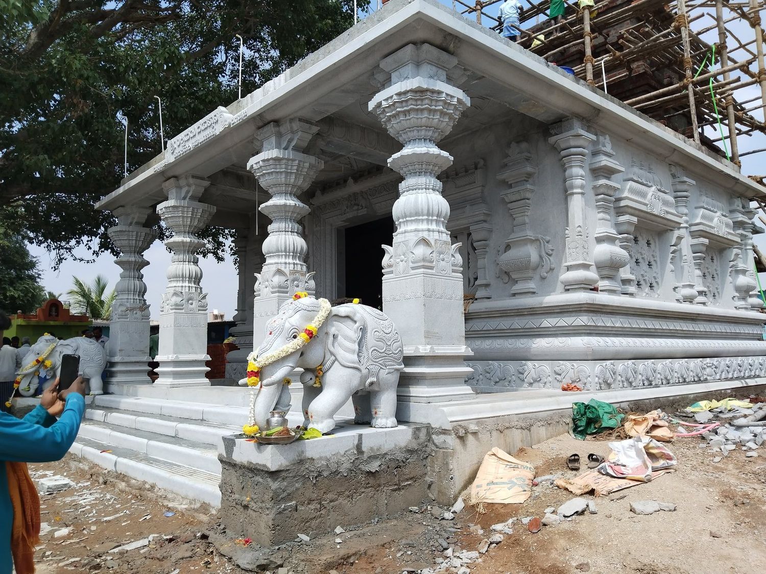 Temple porch with carved columns and a decorated elephant on consecration day