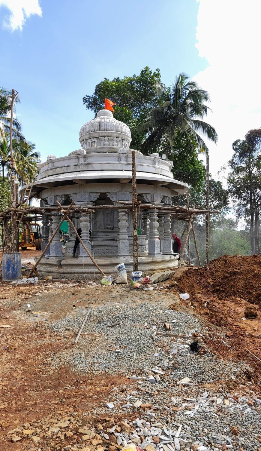 Round stone shrine under construction with scaffolding and a flag