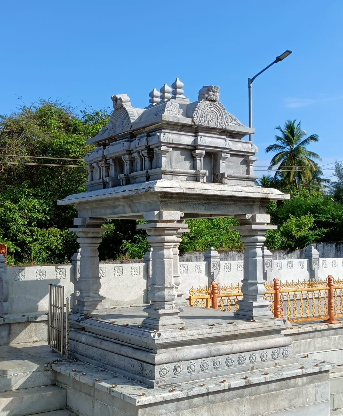 Completed stone shrine with carved roof and surrounding railing
