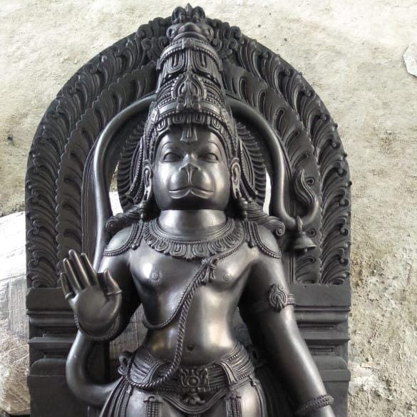 Carved black granite Hanuman murti with a decorated arch surround