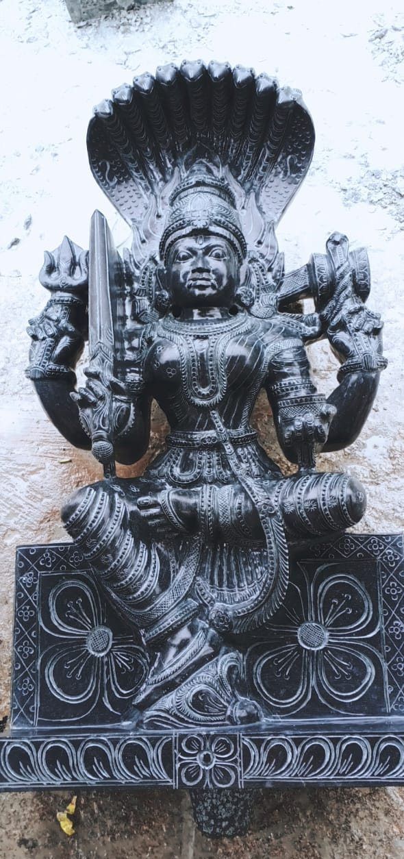 Carved granite deity seated beneath a multi-headed naga hood