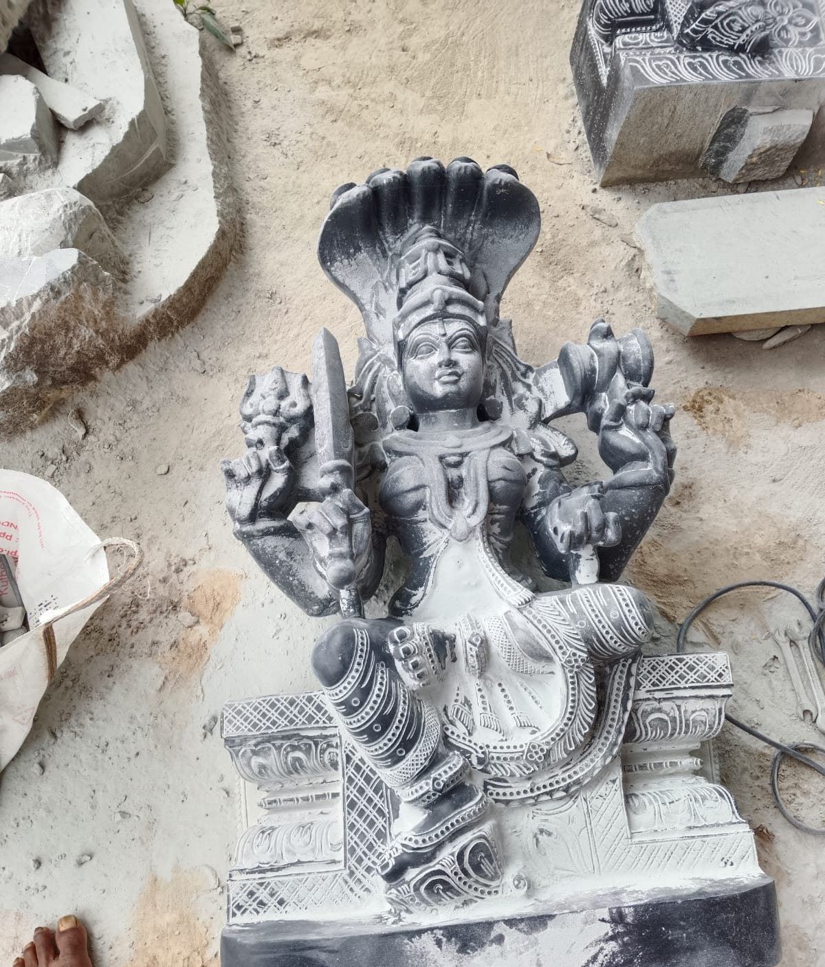 Carved granite seated deity photographed in the workshop yard