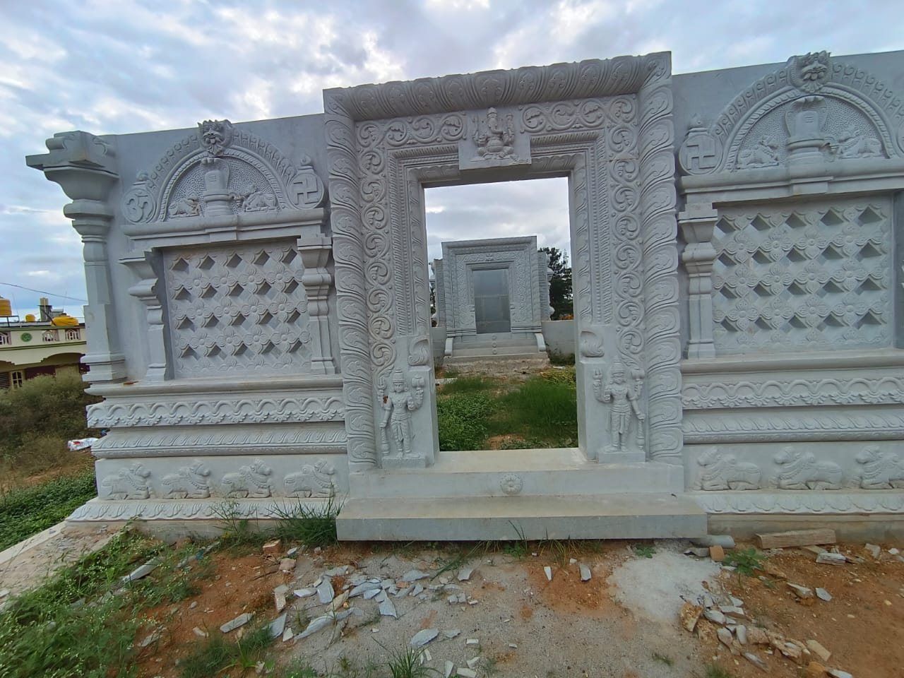 Carved granite compound wall with a decorated doorway surround