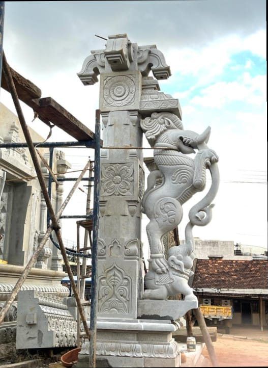 Carved yali column being positioned on site with scaffolding